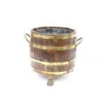 Coopered barrel log basket with brass banding and twin brass handles on brass lion paw feet, with