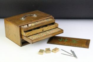 Chinese mahjong set with wooden tiles and metal playing pieces, housed within trays in a wooden case