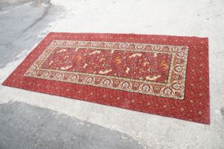 Burgundy ground carpet, the central panel decorated with animals, within a border, 200cm wide x