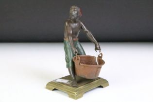 Spelter polychrome figure of a man with bucket, on brass base. Approx 14.5cm high