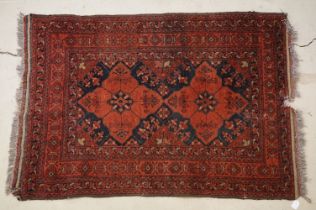 Middle Eastern carpet with two central medallions, red and black ground within geometric borders,