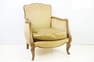 Early 20th century low armchair with oak frame, upholstered in beige with studded edging, on