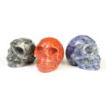 A collection of three carved and polished semi precious stones in the form of human skulls.