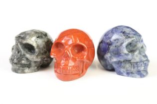 A collection of three carved and polished semi precious stones in the form of human skulls.