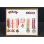 A framed and glazed World War Two medal group of five full size medals together with badges to the