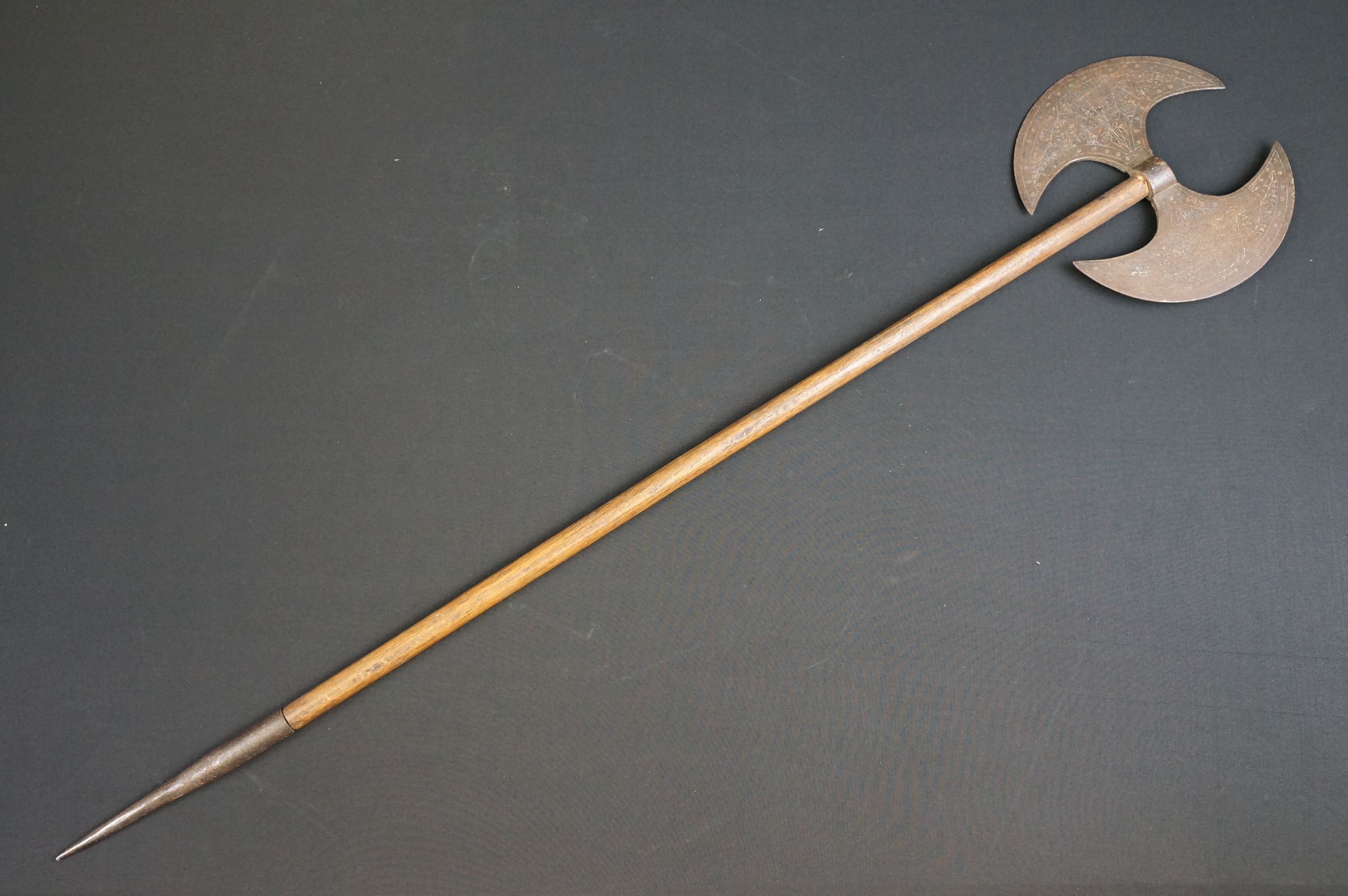 A Persian double headed axe with decorative pattern to the axe head, spike to lower wooden handle.