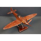 A carved wooden model of a RAF Spitfire on wooden plinth