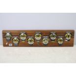 Automobilia - A wall display of nine AA grill badges and AA key, all mounted on a wooden panel. (