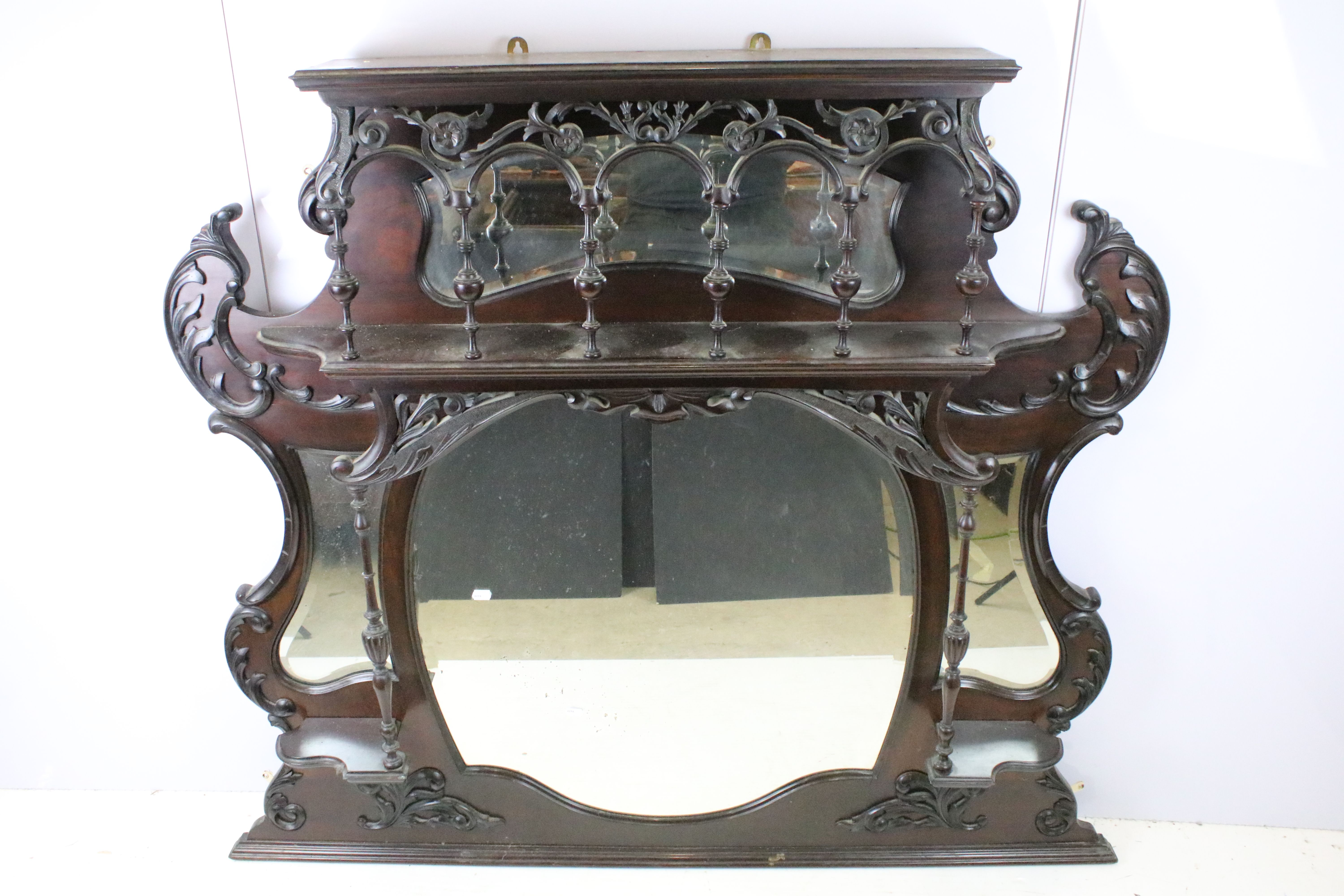 Art Nouveau mahogany overmantel mirror, carved with scrolling flowers and foliage, with two candle