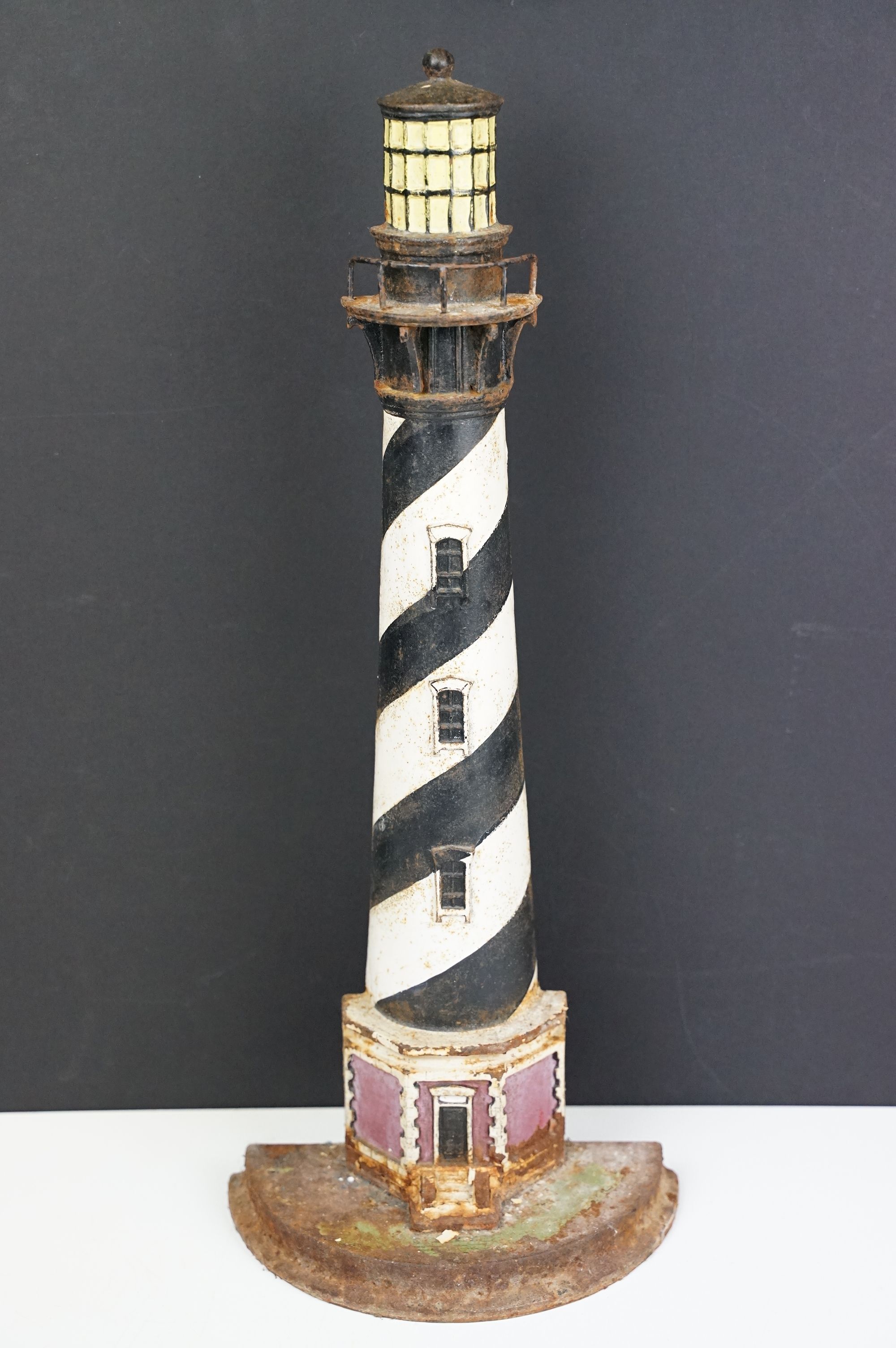 Cast iron doorstop in the form of a lighthouse, with a semi circular base and spiral painted black &