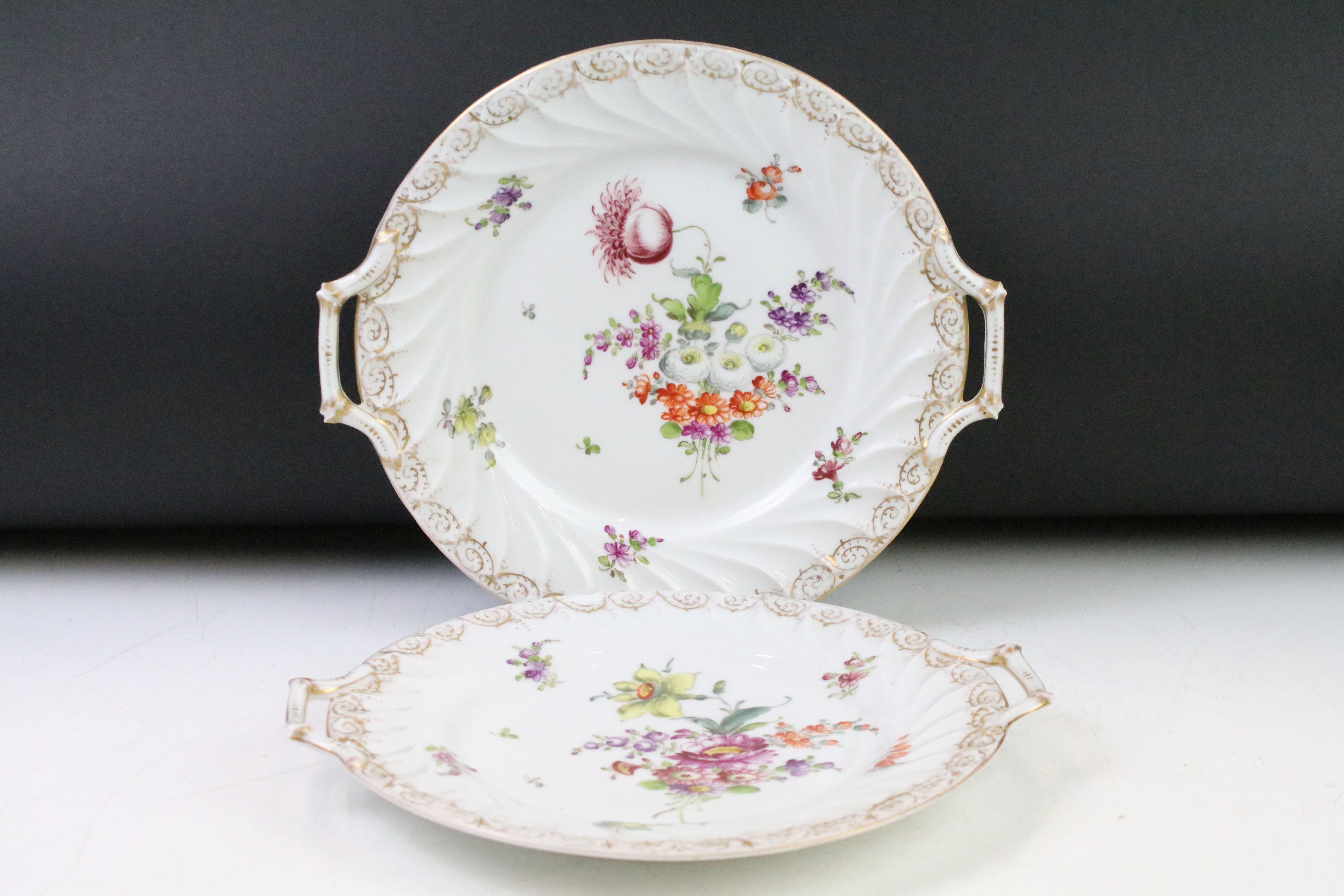 Two Dresden porcelain twin handled plates with hand painted floral decoration and gilt detail to