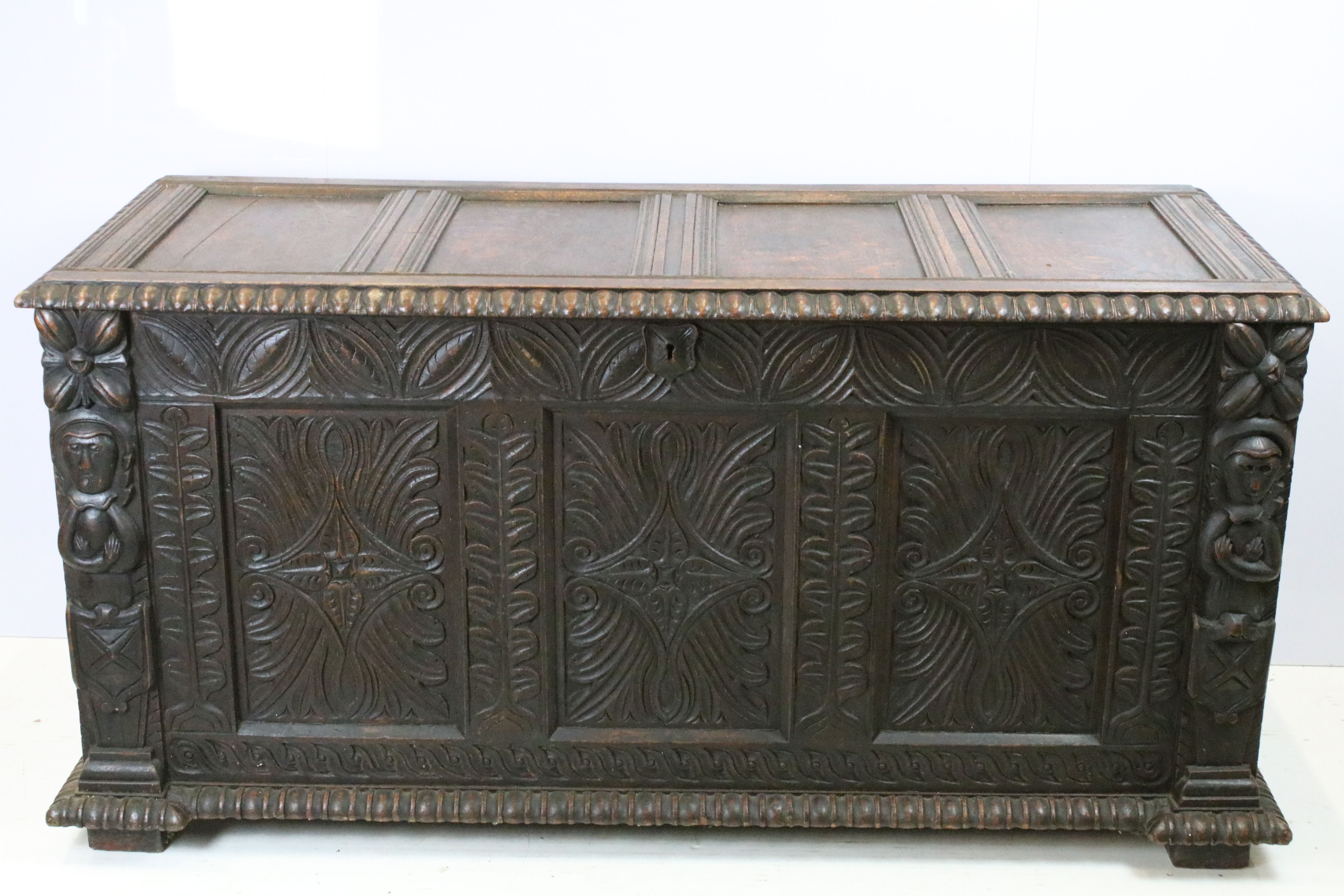 19th century carved oak chest of substantial proportions, the four panelled lid above carved