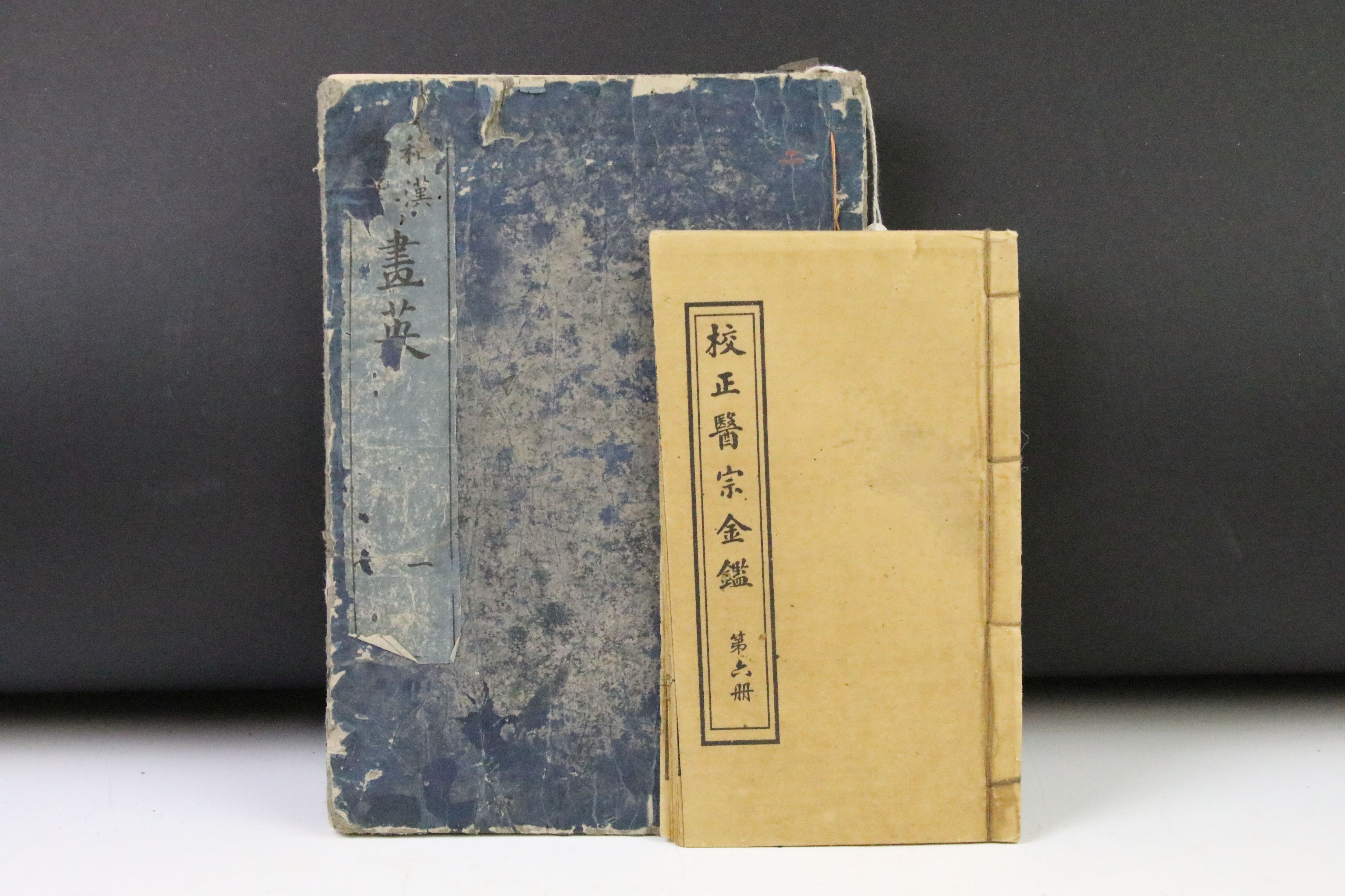 Two antique oriental books one containing a quantity of woodblock portraits and scenes the other