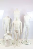 Group of four childrens mannequins together with one torso, all raised on round glass basses.
