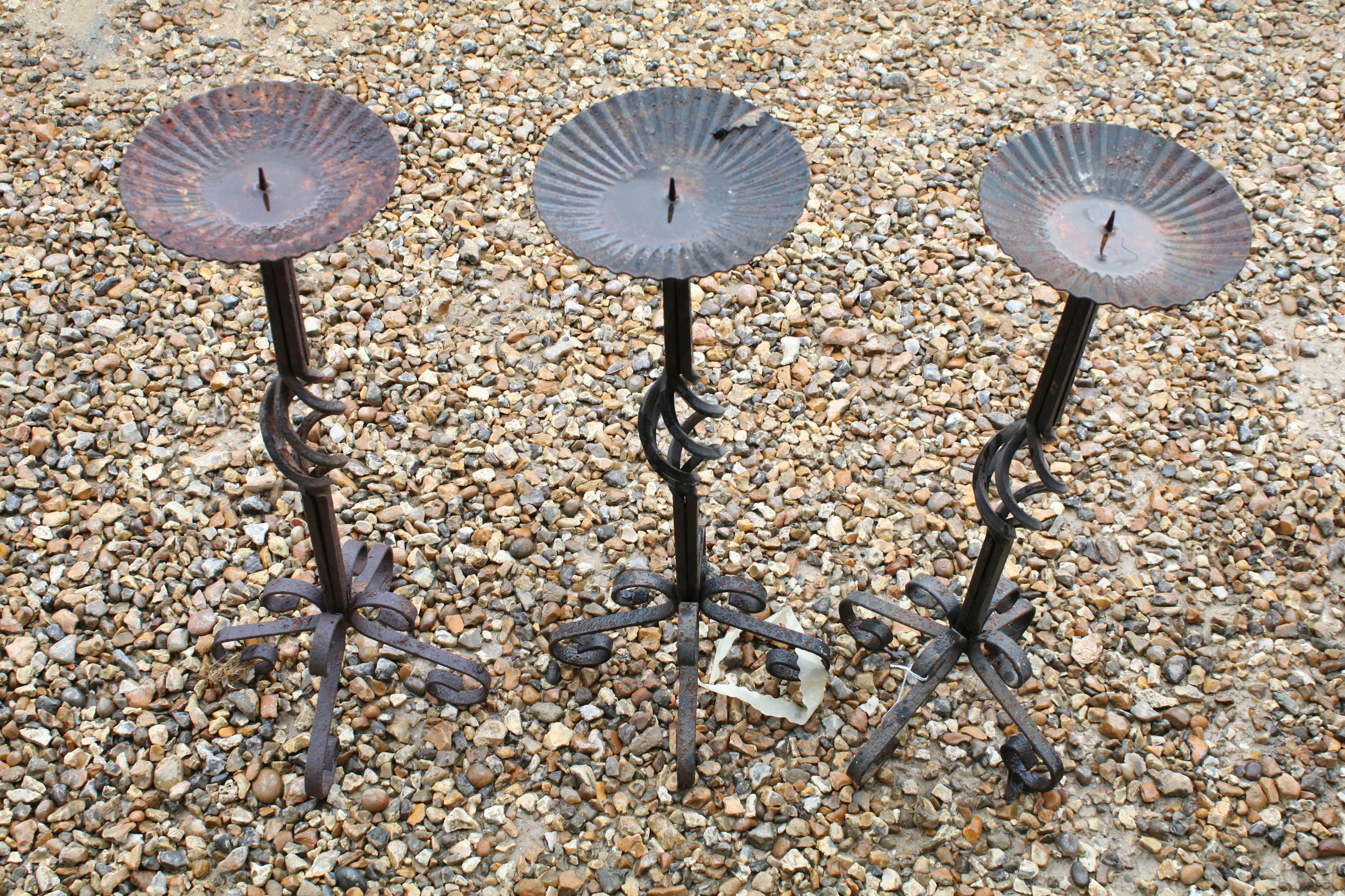 Set of three wrought iron floor standing candlesticks with spiralling to support, approx 62cm high