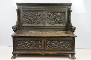 19th Century carved ebonised oak hall bench / settle having panelled back carved with mythical