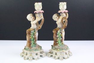 Pair of 19th century Continental porcelain candlesticks modelled with putti, with blue crossed