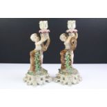 Pair of 19th century Continental porcelain candlesticks modelled with putti, with blue crossed