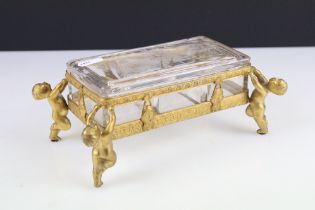 A cut glass lidded dish within decorative gilt stand held aloft by four cherubs.