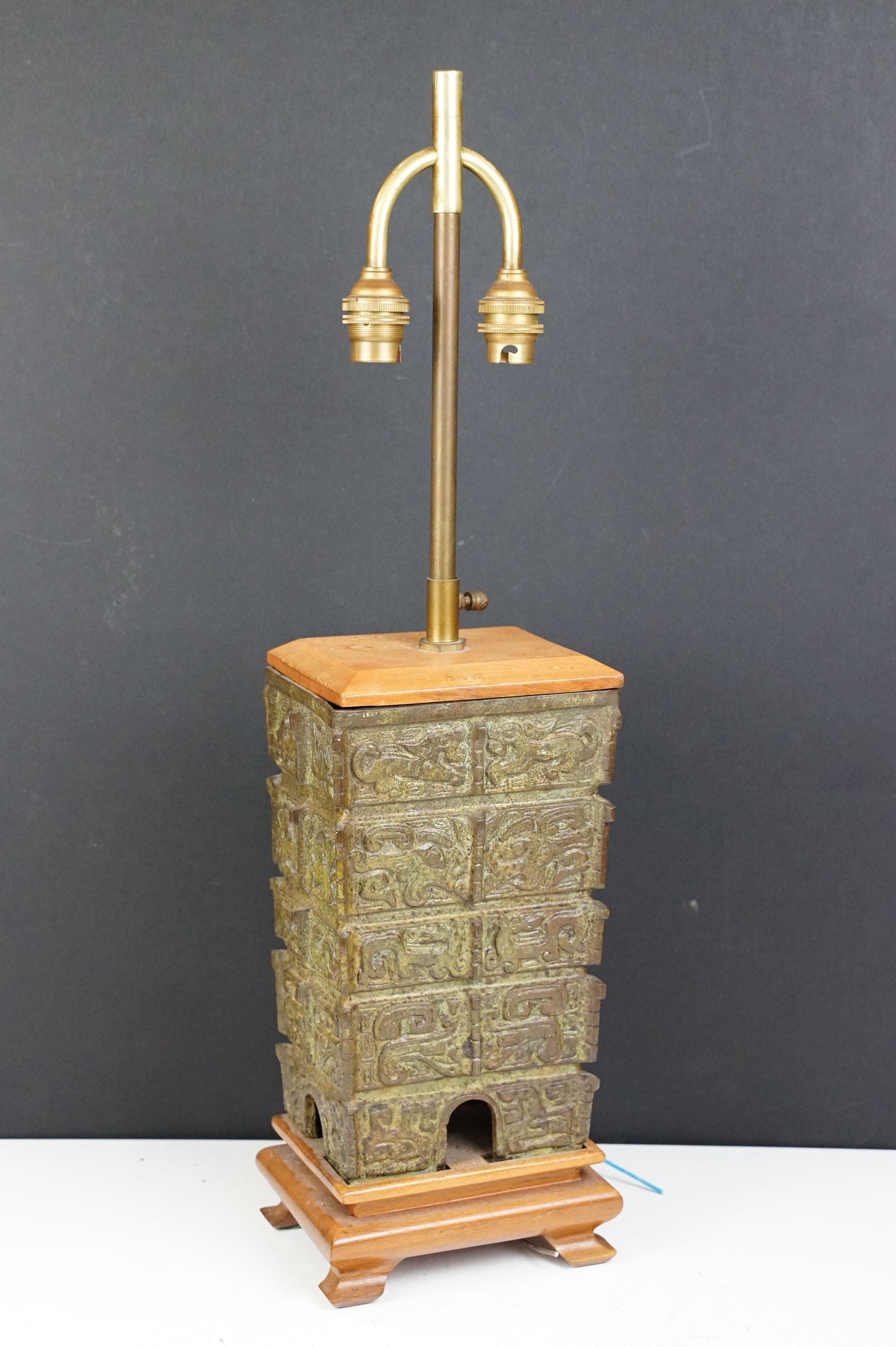 Chinese cast bronze table lamp of structural form with twin-bulb fittings, raised on a wooden