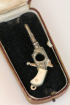 An antique watch winder and cigar cutter watch fob in the form of a pistol with mother of pearl