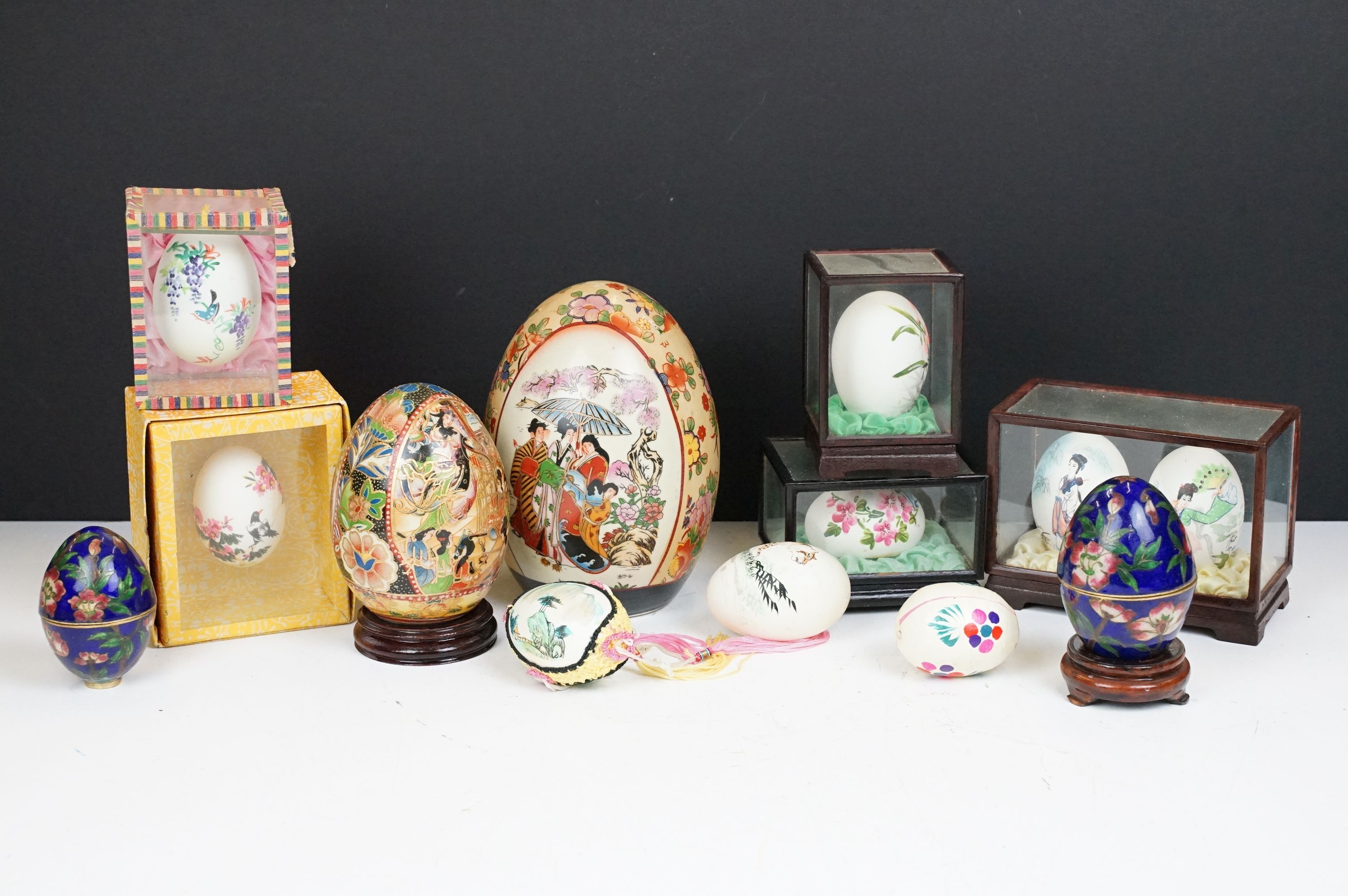 Collection of Chinese painted eggs including some in small display cases, and some ceramic examples.