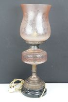 Late 19th / early 20th century oil lamp, the pink glass frosted shade with floral detail, over a