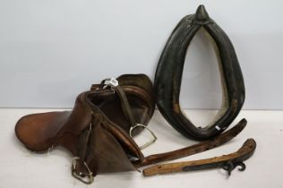 Leather horses saddle with stirrups and neck harness.
