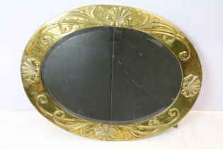 Arts and Crafts mirror of oval form with bevelled glass and hammered brass frame decorated with