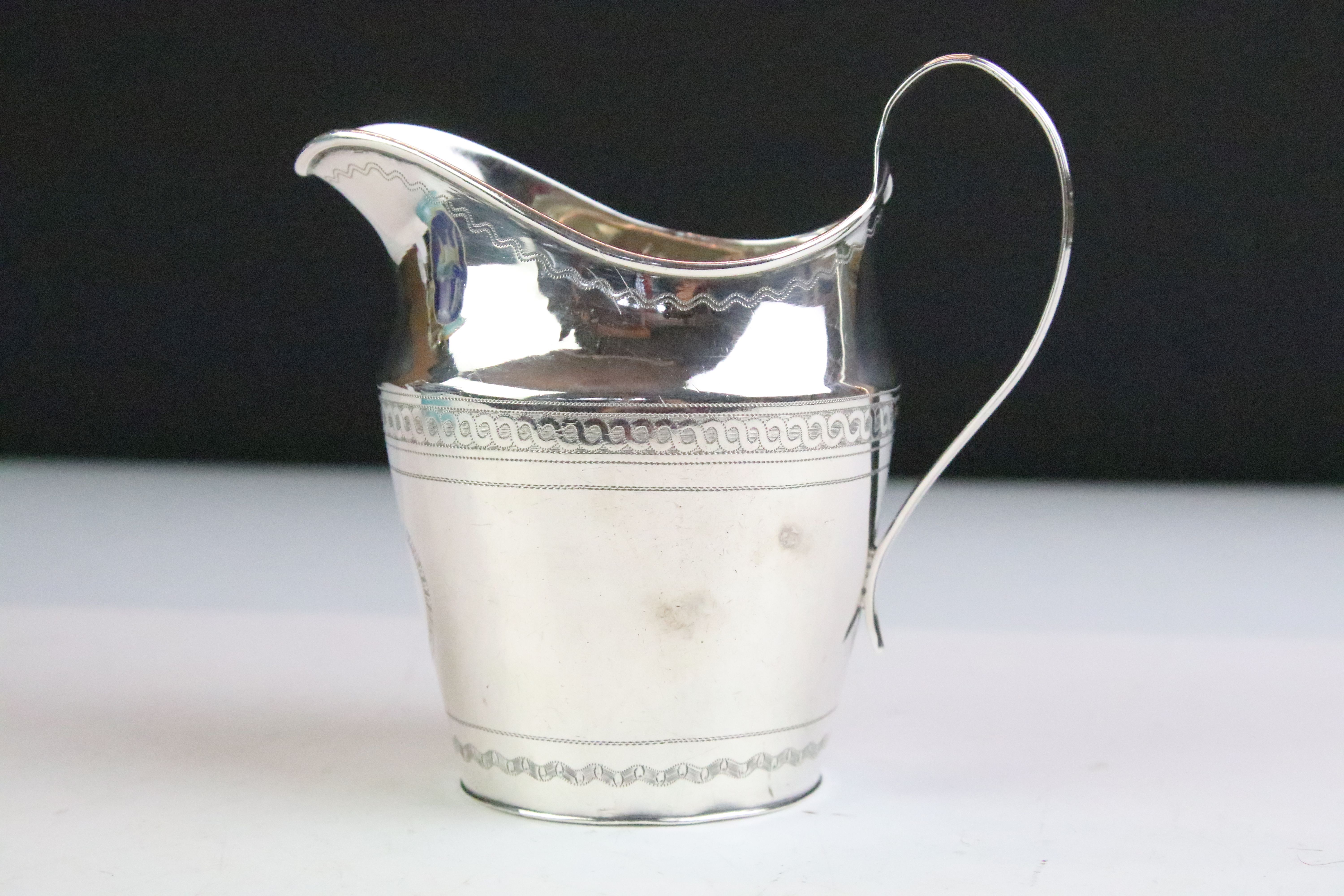 George III silver milk / cream jug with bright cut banding decoration and high loop reeded handle,