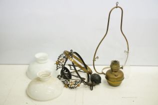 Two ceiling suspended oil lamps to include a brass framed lamp with milk glass shade and a painted