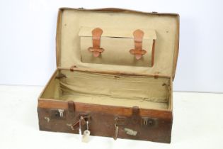 Antique leather suitcase with leather straps and printed initials.