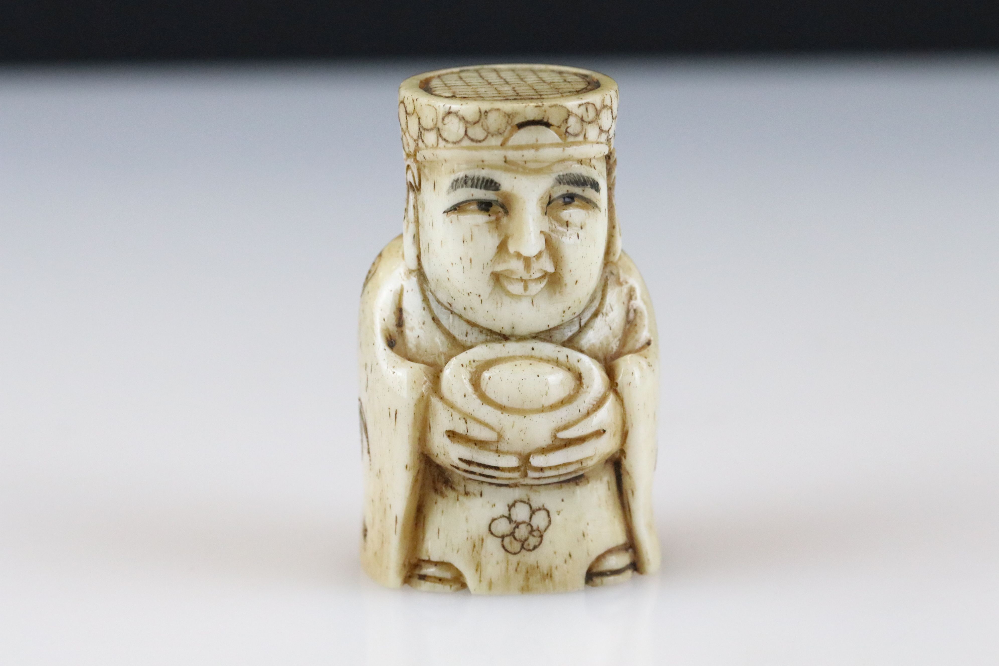 A signed ox bone netsuke of an oriental figure with indigo, approx 5.5cm