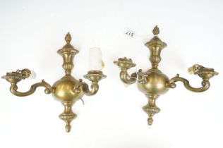 Pair of brass electric wall mounting light sconces having twin arms with and urn design back plates.