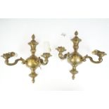 Pair of brass electric wall mounting light sconces having twin arms with and urn design back plates.