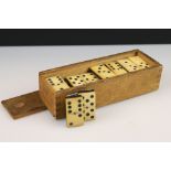 A set of early 20th century bone dominoes within wooden case.