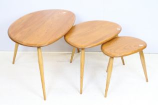 Ercol elm pebble nest of tables each having oval tops raised on tapering turned legs. Ercol