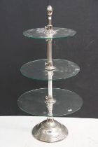 Three tier glass shop display stand raised on a single circular metal foot, approx 81cm tall