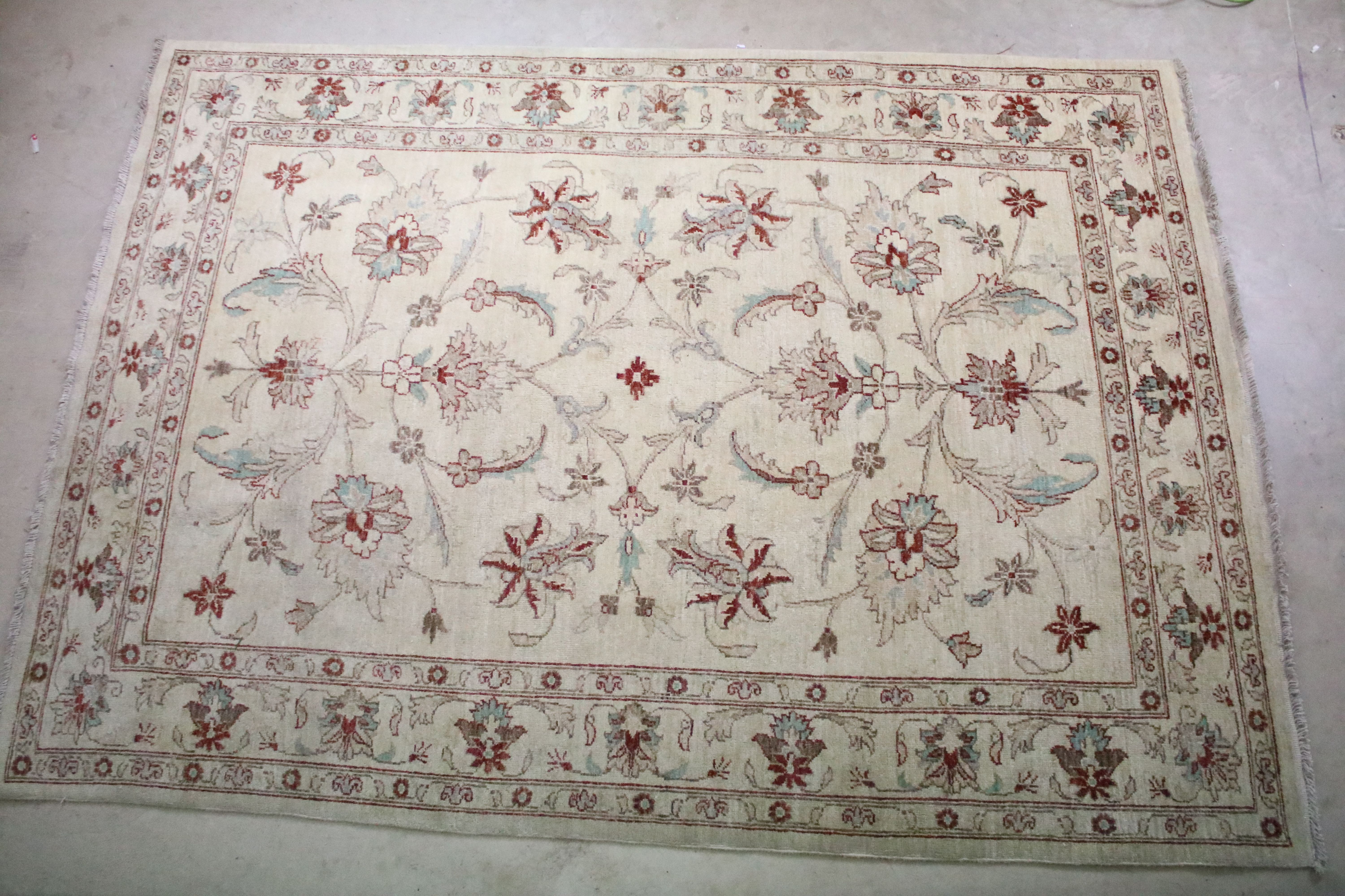 Cream ground rug with floral & leaf decoration and red & brown border, fringed to either end,