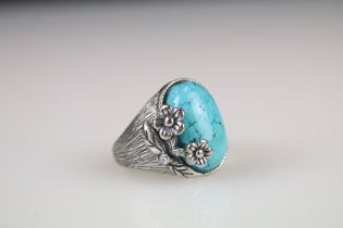 A ladies ring with floral embelishment and set with central turquoise cabochon.