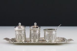 A white metal three piece cruet set with matching tray, complete with salt spoon.