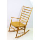 Mid century rocking chair having a curved ladder back with yellow woven cushion seat. Measures 104cm