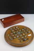 An antique carved wooden solitaire board complete with antique marbles.