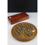 An antique carved wooden solitaire board complete with antique marbles.