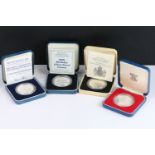 A collection of four Royal Mint silver proof crown coins all encapsulated within display cases.