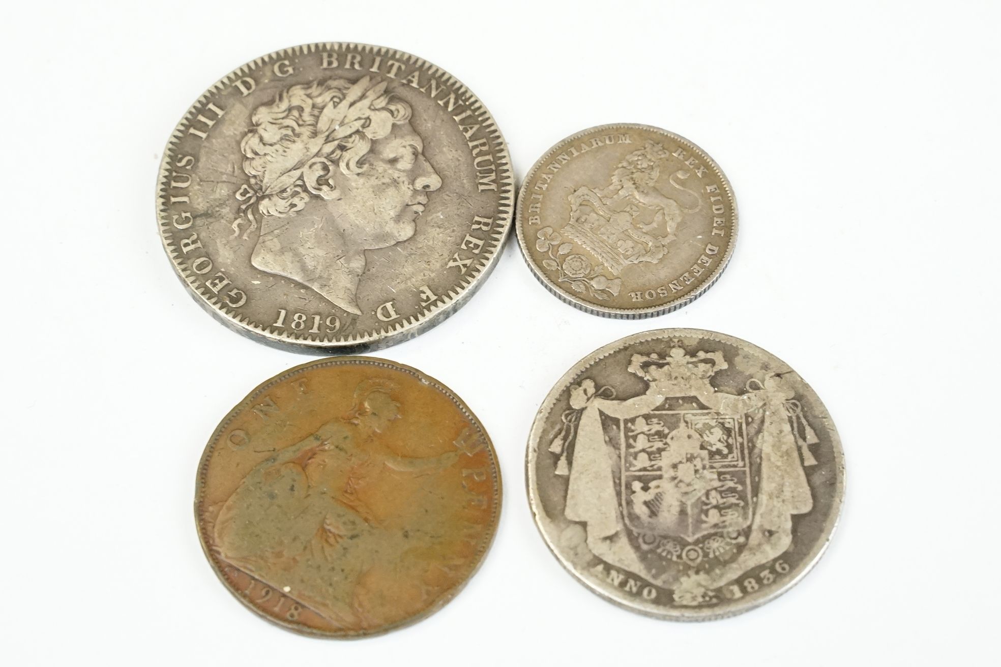 A small group of four British pre decimal coins to include a King George III 1819 full silver