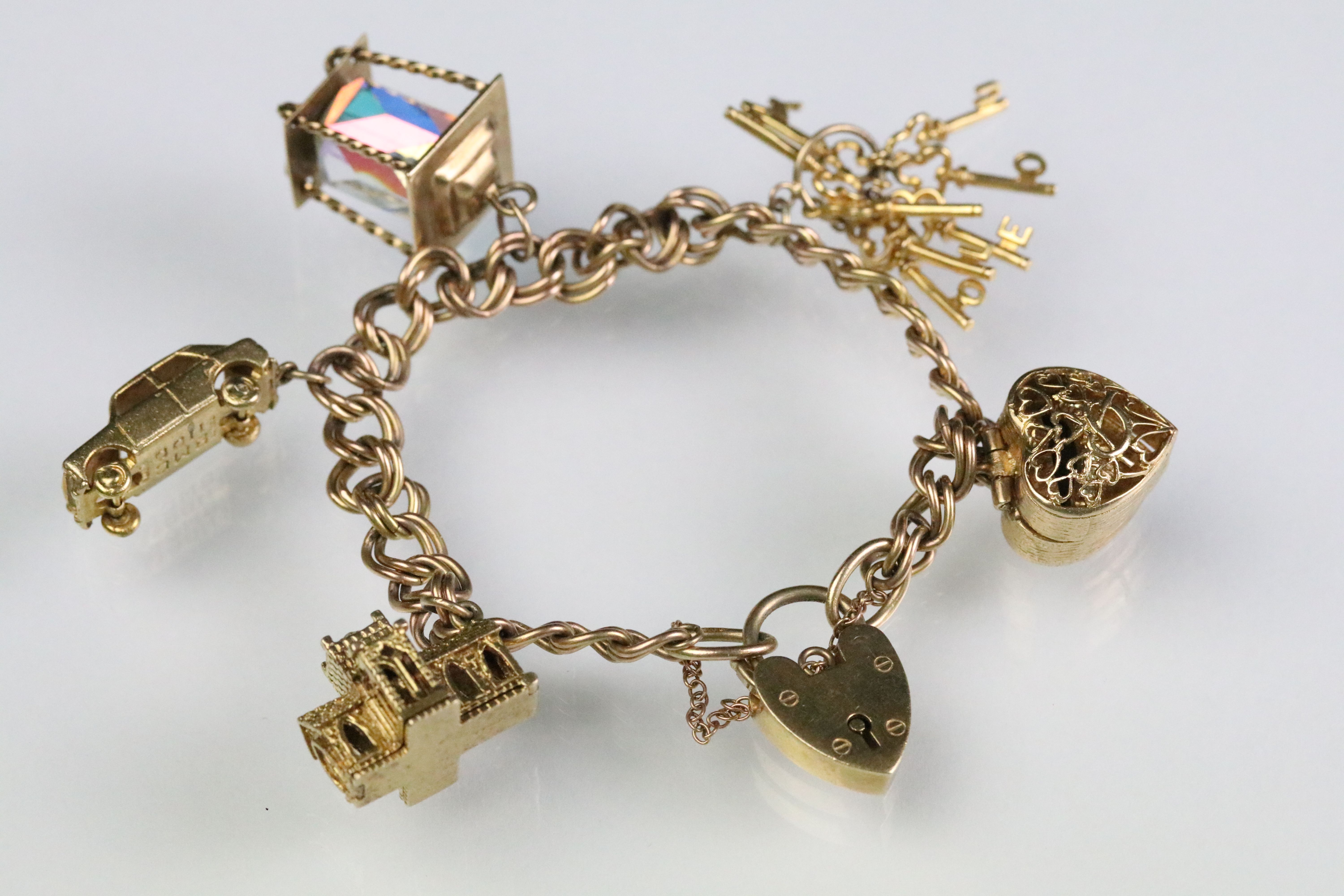 9ct gold hallmarked charm bracelet. The double curb heart lock bracelet mounted with five 9ct gold
