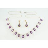 9ct gold and amethyst drop necklace having a fine link chain with thirteen oval cut amethysts in