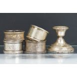 Four assorted silver hallmarked napkin rings together with a silver hallmarked candlestick. Napkin
