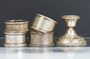 Four assorted silver hallmarked napkin rings together with a silver hallmarked candlestick. Napkin